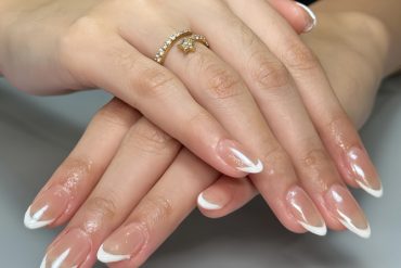 Almond-shaped nails with clear glossy base and curved white French tips