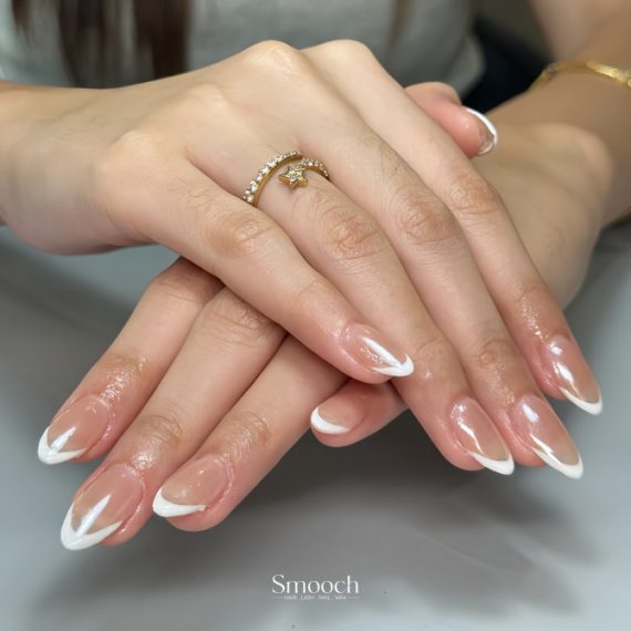 Almond-shaped nails with clear glossy base and curved white French tips