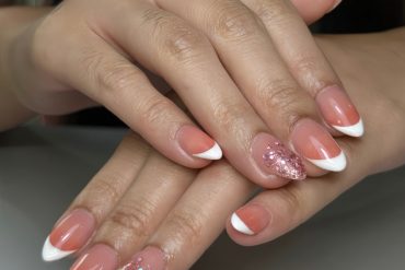 Almond-shaped nails with rose-pink base, white French tips, and pink glitter accent nails