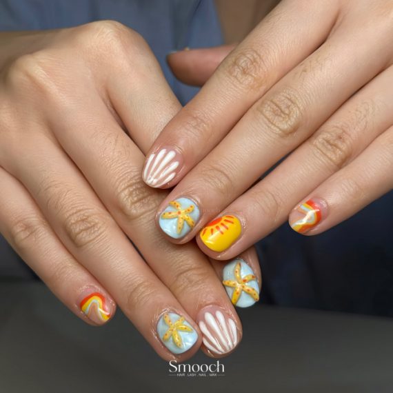 Short round nails with tropical swirl designs, sun motifs, white shell stripes, and 3D starfish accents
