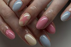 Glossy oval nails in pastel pink, blue, and yellow with one watercolor-blend accent nail