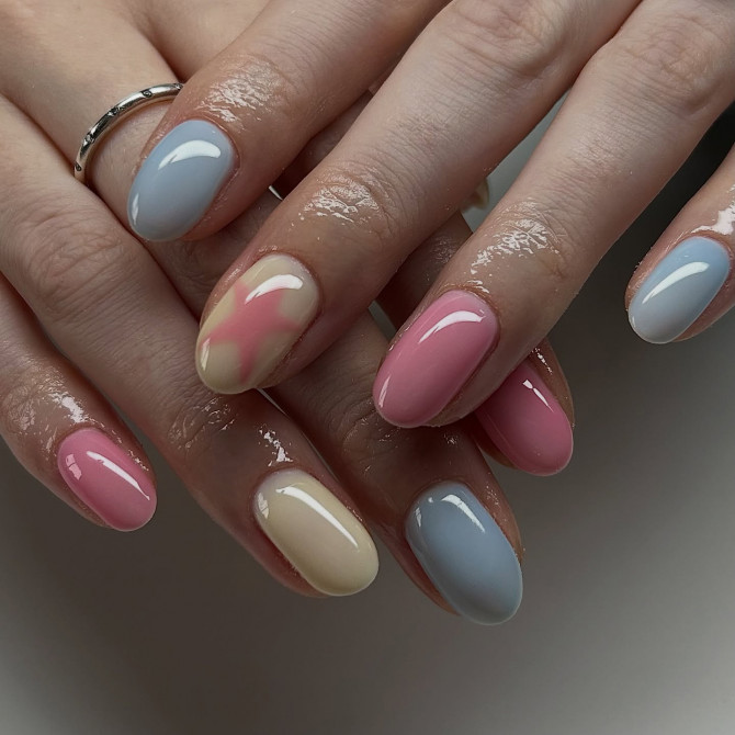 Glossy oval nails in pastel pink, blue, and yellow with one watercolor-blend accent nail
