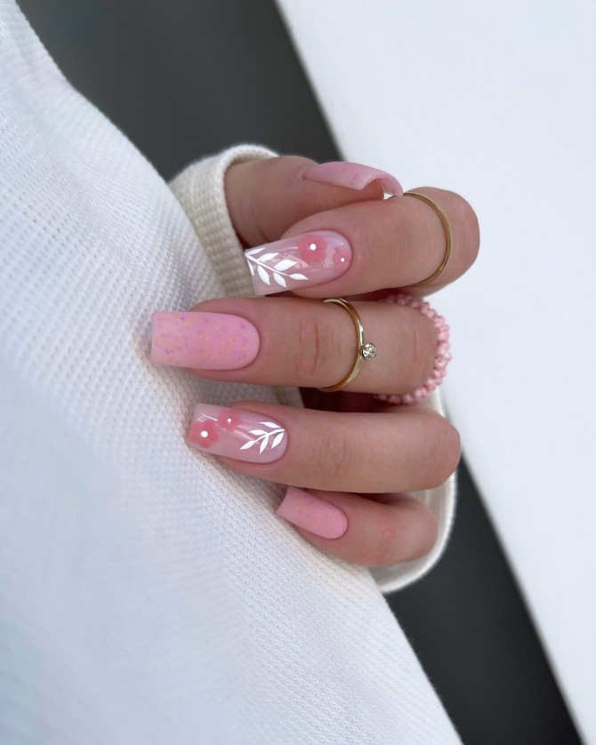 Coffin-shaped nails in soft pink with gold specks and white leaf designs