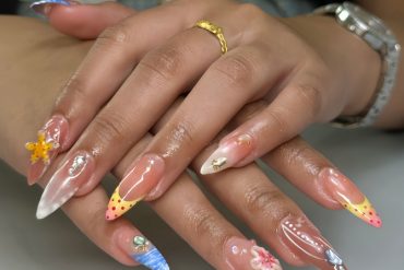 Long almond nails with nude base, 3D flowers, dotted tips, ocean waves, and pearl embellishments