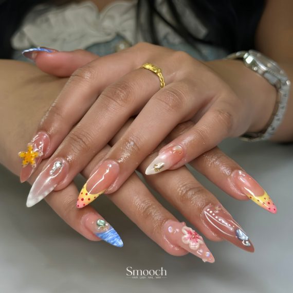 Long almond nails with nude base, 3D flowers, dotted tips, ocean waves, and pearl embellishments