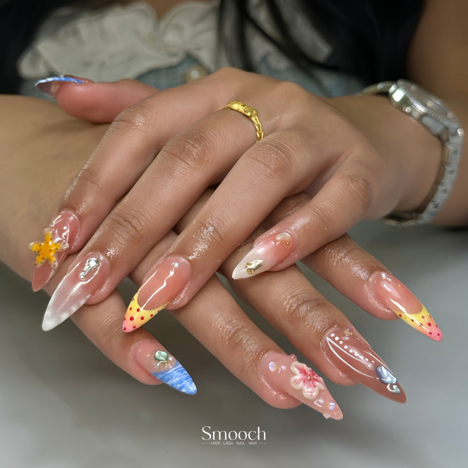 Long almond nails with nude base, 3D flowers, dotted tips, ocean waves, and pearl embellishments