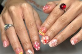 Short square nails with red-yellow dotted French tips, floral designs, and pink marble swirls