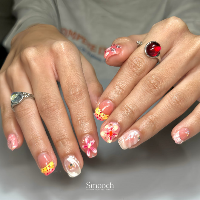 Short square nails with red-yellow dotted French tips, floral designs, and pink marble swirls
