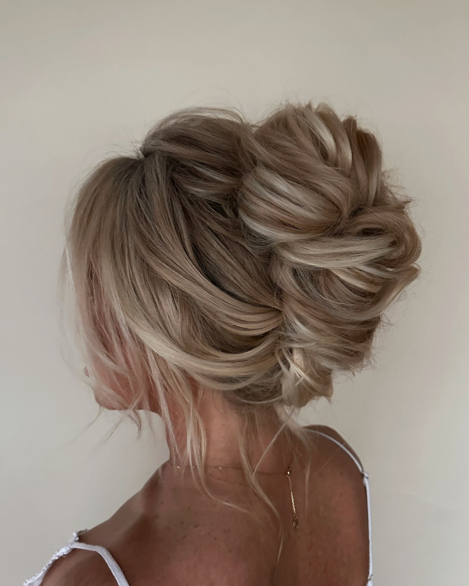 Voluminous bridal updo with tousled blonde texture.