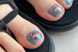 Blue glitter toe nails with Hello Kitty and bear stickers on big toes, beach theme style.