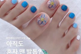 Toe nails painted in blue gradient shades with cartoon-style flower art on the big toe, giving a fun and summery vibe.