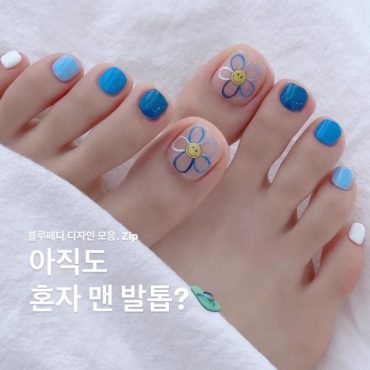 Toe nails painted in blue gradient shades with cartoon-style flower art on the big toe, giving a fun and summery vibe.