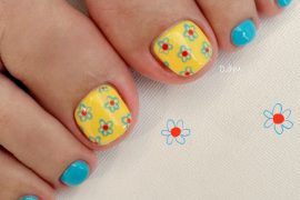 Bright yellow and aqua blue toe nails with daisy floral prints, a cheerful and playful summer pedicure