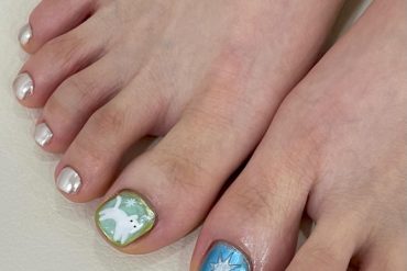 Toe nails with metallic silver polish and big toes featuring white dove on green and star art on blue background