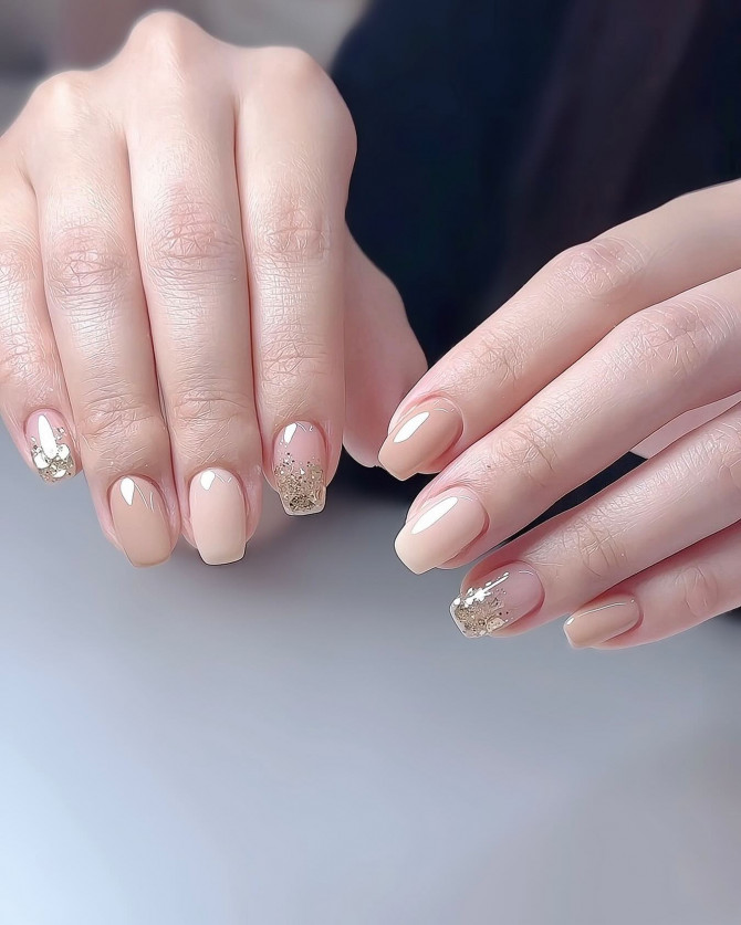 Short bridal nails with champagne nude base and glittery gold accents – perfect for a wedding