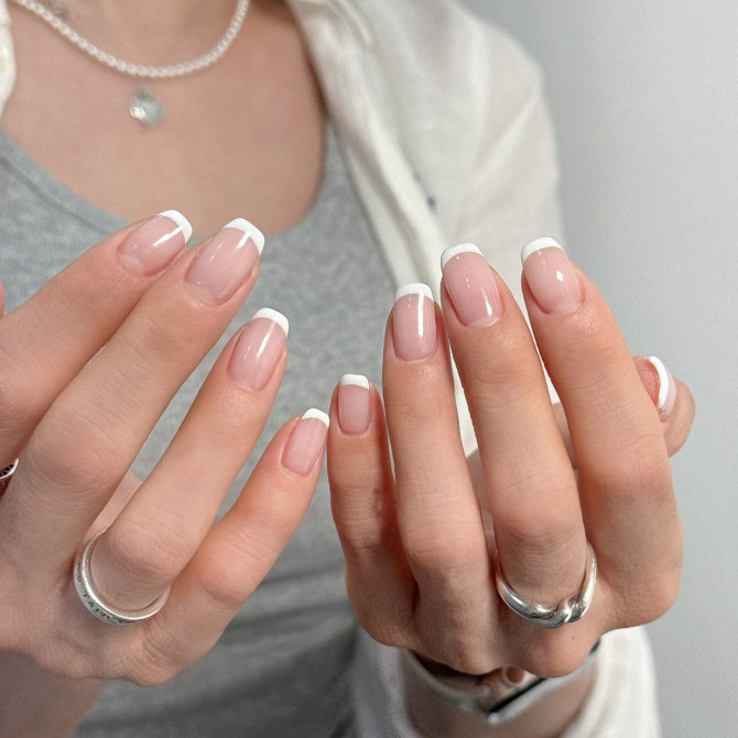 Short rounded nude nails with classic white French tips, natural and timeless style.