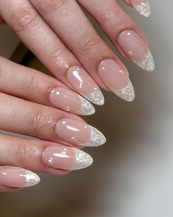 Elegant clear French bridal nails with nude base, almond shape, and tiny pearl accents for a modern minimalist wedding look.