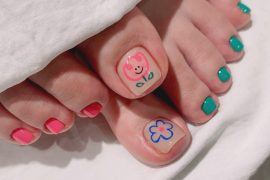 Toe nails with hand-drawn smiling flower and daisy designs paired with bold pink and teal polish