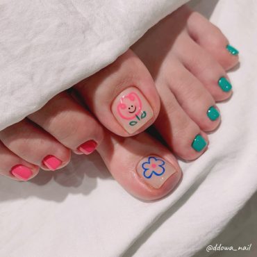 Toe nails with hand-drawn smiling flower and daisy designs paired with bold pink and teal polish