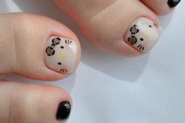 Toe nails with nude base and Hello Kitty face design paired with glossy black polish on smaller toes