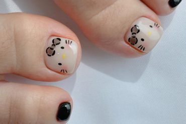 Toe nails with nude base and Hello Kitty face design paired with glossy black polish on smaller toes