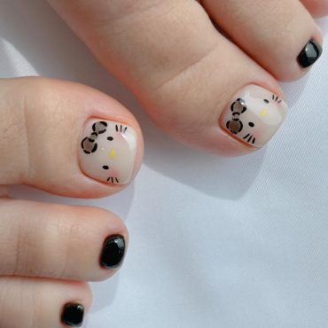 Toe nails with nude base and Hello Kitty face design paired with glossy black polish on smaller toes