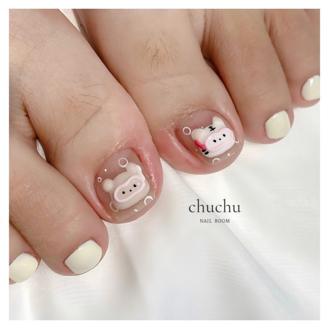 Toe nails with nude base and 3D piggy and bunny designs, paired with off-white polish on surrounding toes