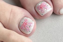 White toenails featuring pink ribbon bow art with glitter dots, designed for a soft and feminine spring look