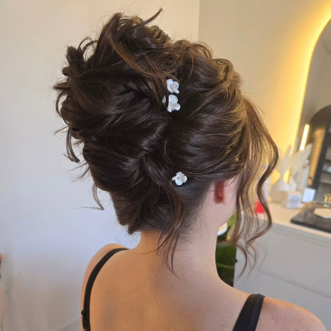  Voluminous dark bridal updo with white floral pins and soft tendrils.