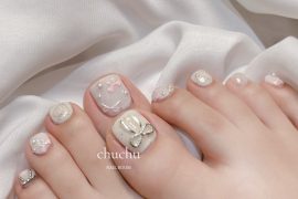 Toe nails with pastel base, pearl and crystal accents, 3D bows and shimmer design in soft square shape