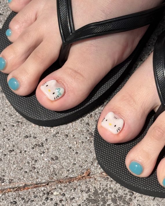 Hello Kitty toe nail art with teal polish and character face on big toe