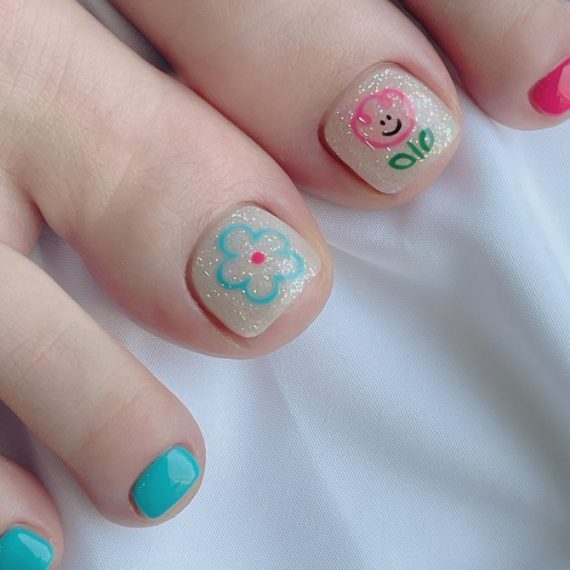 Glitter nude toenails with pink bear and aqua flower design, paired with vibrant turquoise and pink accents