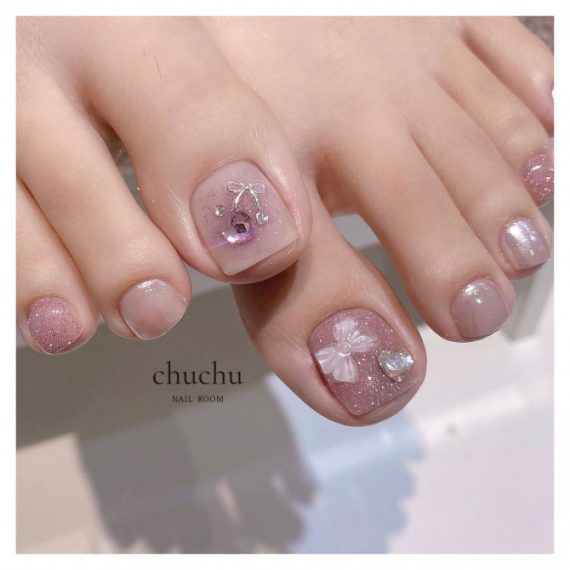 Soft pink toe nails with shimmer finish, crystal cherry and 3D bow embellishments in neat square shape