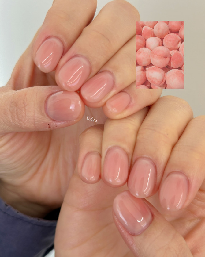 Short oval nails in glossy peach nude shade with jelly finish, clean and elegant on warm skin.