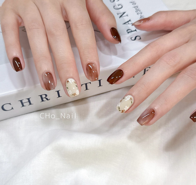 Gradient coffee brown nails with white floral accents on beige background