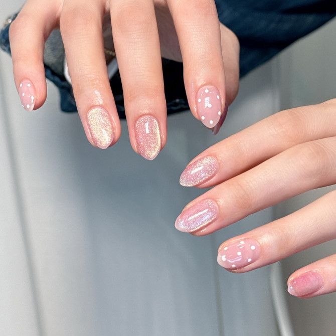 Oval sheer pink nails with iridescent shimmer and white polka dot floral accents.