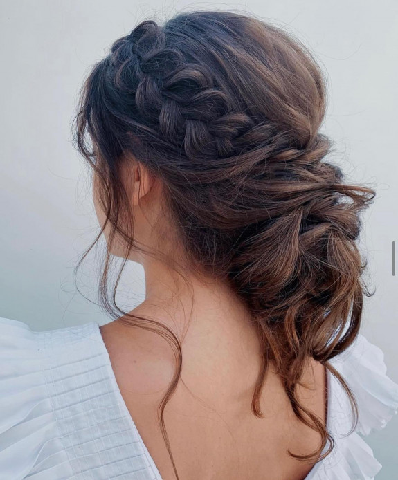 Voluminous braided bridal updo with soft brunette waves.
