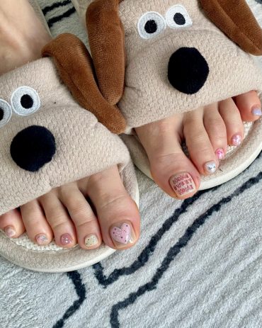 Toe nails with heart design, red love message, and pastel polka dots on a nude-pink base