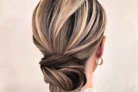 Elegant low twisted bridal updo with blonde and ash brown highlights. Elegant bridal hairstyle with crown braid and floral bun.