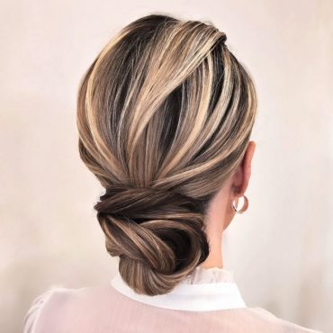 Elegant low twisted bridal updo with blonde and ash brown highlights. Elegant bridal hairstyle with crown braid and floral bun.