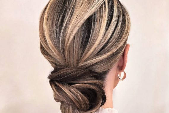 Elegant low twisted bridal updo with blonde and ash brown highlights. Elegant bridal hairstyle with crown braid and floral bun.