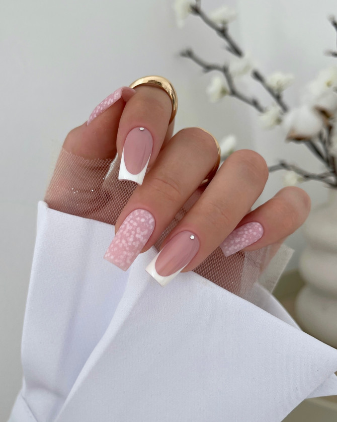 Long square nails in pink and nude, featuring petal dot art, French tips, and a rhinestone accent.