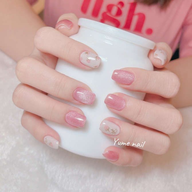 Short square nails with pink shimmer polish and nude base with gold leaf accent designs.