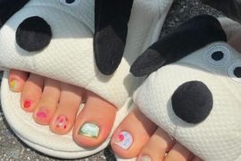 Toe nails with mix of fruit art, cartoon faces, and bright summer colors in a playful and casual design