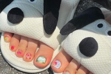 Toe nails with mix of fruit art, cartoon faces, and bright summer colors in a playful and casual design