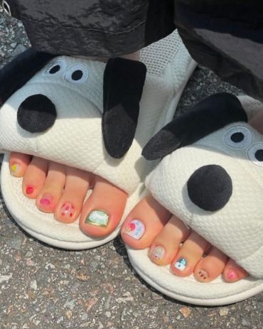 Toe nails with mix of fruit art, cartoon faces, and bright summer colors in a playful and casual design