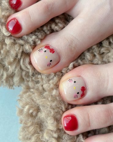 Square toe nails with Hello Kitty design on nude base and surrounding toes painted in glossy red