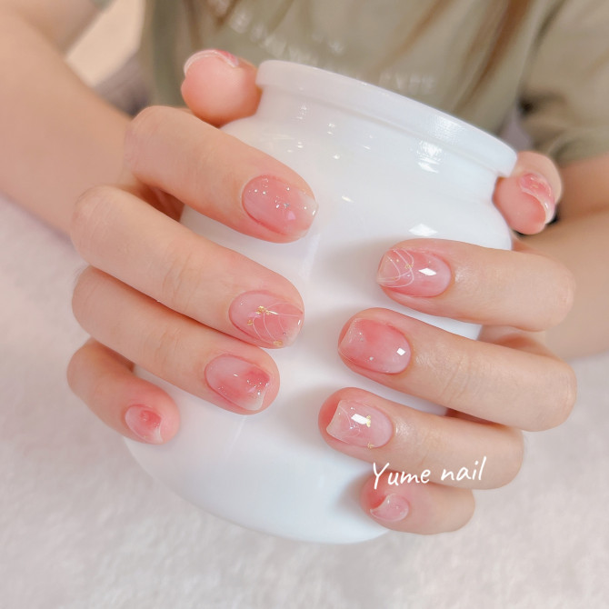 Short oval nails with sheer pink jelly base, gold flake accents, and fine white petal line art.