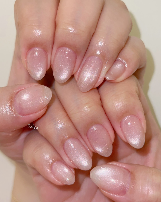 Medium almond-shaped nails in sheer nude pink with fine shimmer overlay and glossy finish.