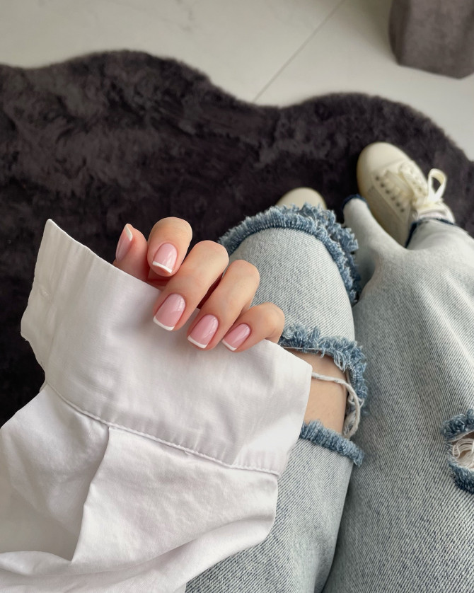 Short pink nude nails with thin white French tips in a classic summer style